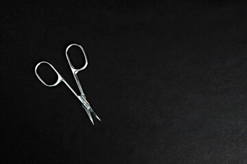 metal nail scissors on a black textured background