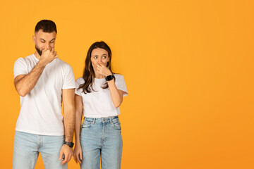 Concerned young couple with hands over their mouths, displaying shock or surprise