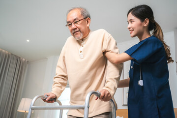 Obraz premium Asian physiotherapist nursing home to support old senior man patient therapy by walker, caregiver nurse help recovery health care with elderly retirement man person at home, health insurance concept