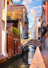 Channel in Venice with stone bridge and old authentic venice italian houses. Sunny day town of Venezia. Popular travel location Europe.