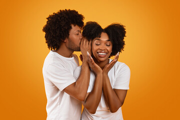 Black guy whispering something on his girlfriend ear