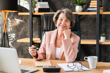 Portrait of senior businesswoman tutor teacher lecturer working at desk in office using laptop...