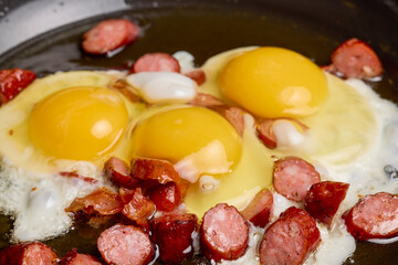 fried eggs with sausages in a pan.
