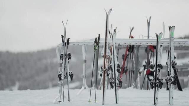 Multiple skis on ski rack winter Christmas December janauary cloudy gray snowy Aspen Buttermilk Snowmass Highlands AJAX top of Rocky Mountains lodge skier wilderness smooth gimbal pan right slowmotion