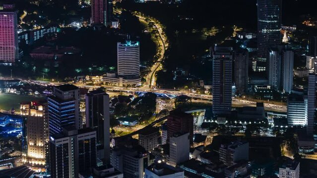 breathtaking night scene over Kuala Lumpur, displaying the city's bright lights, busy roads, and a mix of modern skyscrapers and traditional buildings