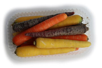 Bunch of variety of different colors of carrots ina plastic box on white background. Organic healthy rainbow carrots 