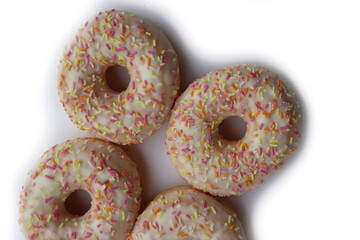 Many donuts with white glaze and yellow, orange and pink sprinkles isolated on white background