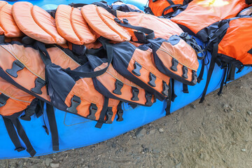 Good quality orange life jackets lined up on a blue boat. Safety equipment for water activities: Life jackets are available for rafting customers.