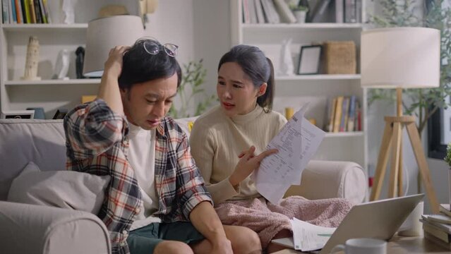 upset asian couple counting overspent budget,Unhappy young woman feeling stressed calculating monthly expenses at home,lack of money for utility household or rental payments, bankruptcy concept