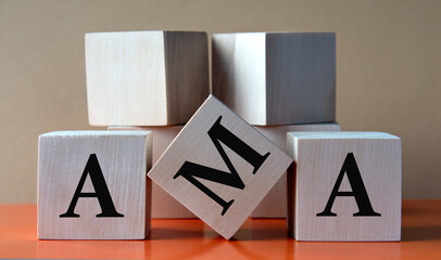 AMA - acronym on large wooden cubes on light brown background