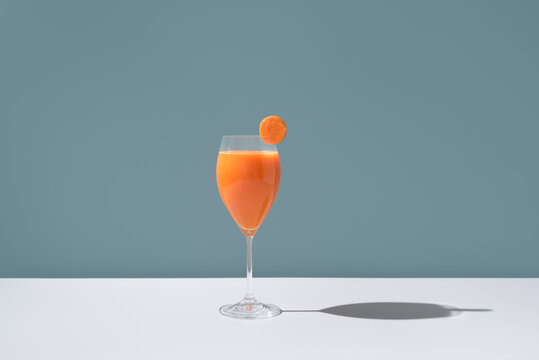 Elegant glass of carrot juice with a slice on the rim
