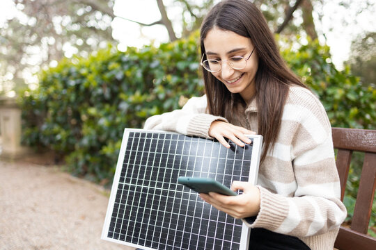 Young woman learning about solar panels in a park