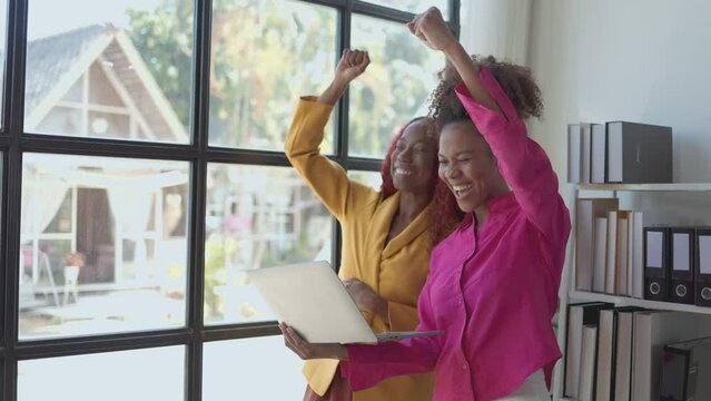 Two African American business women are talking about their business victory with cheerful and spent a really good time together in a private office after working hard so many day.