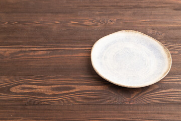 Empty blue and white ceramic plate on brown wooden. Side view, copy space