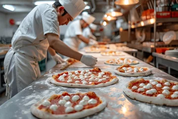 Tuinposter Pizza chef finishing the preparing of in professional pizzeria restaurant kitchen. © jakapong