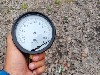 A man holds a broken pressure gauge or mechanical manometer, performs maintenance and replaces...