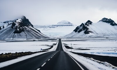 a road in the middle of a snowy landscape with mountains in the background 