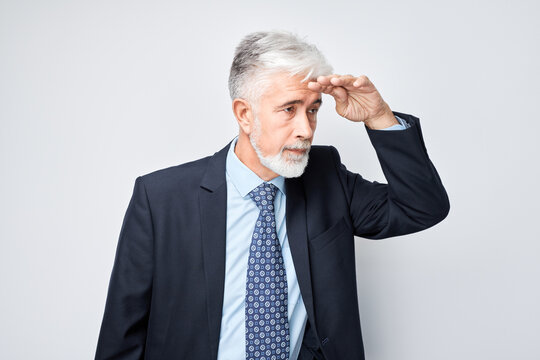 Senior businessman looking away with hand on forehead, concern or deep thought on light background
