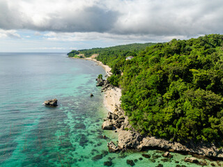 Sun reflection on tropical beach with coral reefs in turquoise sea water. Carabao Island. Jose, Romblon. Philippines.