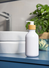 White soap dispenser near basin and green monstera in blue and grey bathroom, close up, mockup