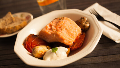 Simmered slice of salmon with tomato spinon and coconut sauce in a white bowl