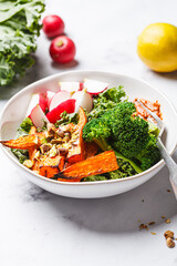 Vegan bowl with kale, broccoli, baked sweet potato, radish and red pesto.