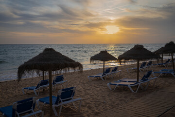 Sunset on the beach with sunbeds and umbrellas