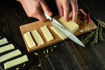 The chef hands use a knife to cut the cheese into small pieces for tasting. Presentation of a delicious Mozzarella milk cheese recipe