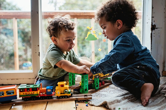 Two Young Boys Playing With a Toy Train Set. 