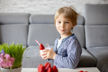 Sweet preschool child, boy, eating belgian waffle with strawberries and chocolate at home