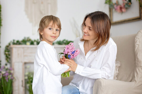 Cute little boy, giving flowers to his mom for Mothers day.