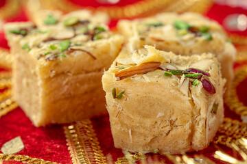 Traditional Indian sweets on a decorative red fabric with golden embroidery