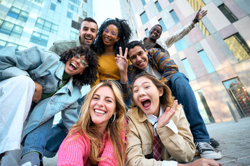 A group of happy people is sharing a fun moment. Young friends take a selfie picture during a leisure event. The team is traveling together. Smiling community portrait looking at camera - obrazy, fototapety, plakaty