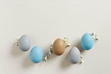 Easter Aesthetic with Matte Eggs and Delicate Florals, painted chicken egg decorated white flowers, top view on beige background, spring holiday concept. Minimal style pattern in pastel tones