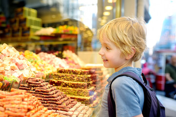 Cute boy looking on showcase of confectionery shop with traditional turkish sweets baklava. Child...
