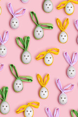 Cute Easter eggs with colorful Bunny Ears and smile on faces on Pink Background, Creative Flat lay pattern, holiday concept. Festive decoration idea for wooden eggs, Top view funny Easter Bunny