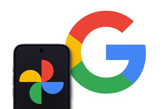 Google Photos logo is displayed on a modern smartphone, photo sharing and storage service developed by Google, big Google logo in the background