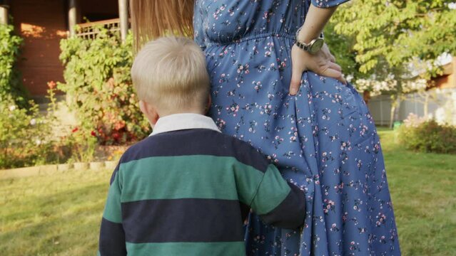 Little boy hearing his pregnant mom's belly outdoor 