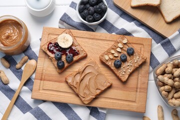 Different tasty toasts with nut butter and products on white wooden table, flat lay