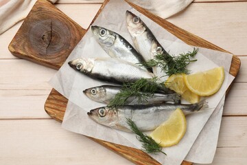 Fresh raw sprats, lemon and dill on light wooden table, top view