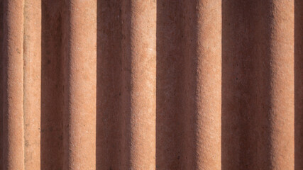 Wavy orange background with shadows. Red wavy wall in the sun