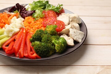 Balanced diet and healthy foods. Plate with different delicious products on light wooden table, closeup