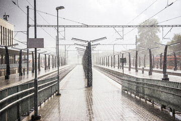 Heavy rain on train station. Wet platform landscape. Stron rain background. Raindrops grain. Transportation background rainy day. Bad weather conditions for vacation.