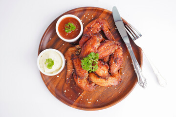 Cooked grilled chicken wings marinated with seasonings Placed on an old wooden tray on a white background