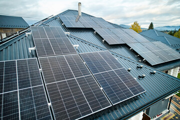 Obraz premium Photovoltaic solar panel system on the roof of house. Modern solar modules installed on house. Concept of alternative, renewable energy and home autonomy.