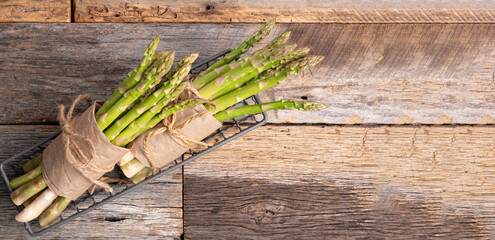 Bunch of branches of fresh green asparagus on wooden background, top view.
