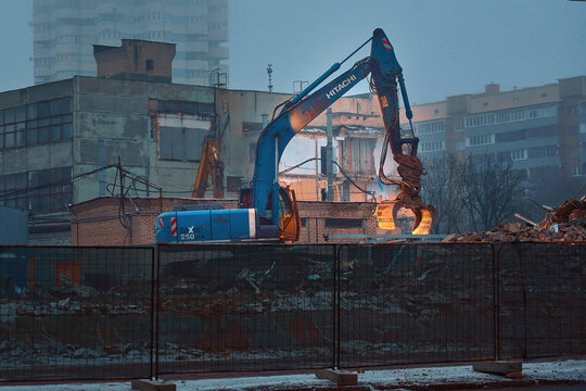 Minsk, Belarus. Feb 11, 2024. Hitachi Zaxis 250 LCN excavator with grapple removes waste after demolishion building at demolition yard. Removing rubbles from construction site early in the morning
