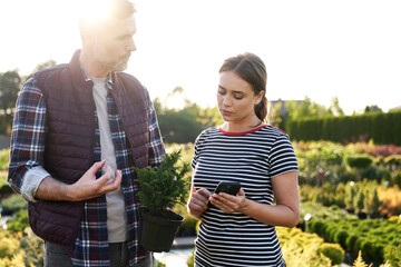 Worker advising the client over plants in garden center