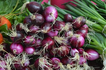The stall displays fresh, vibrant purple onions, their skins glistening under the light. Customers...
