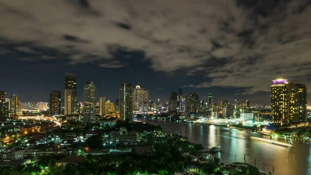 Time lapse of Bangkok cityscape river side with Chao praya river under the cloud on sky at night time